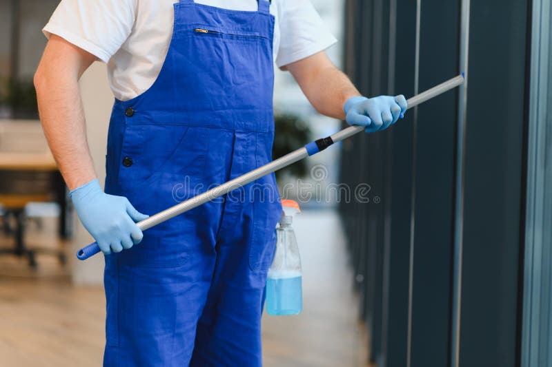 Professional window cleaner using a squeegee on office windows